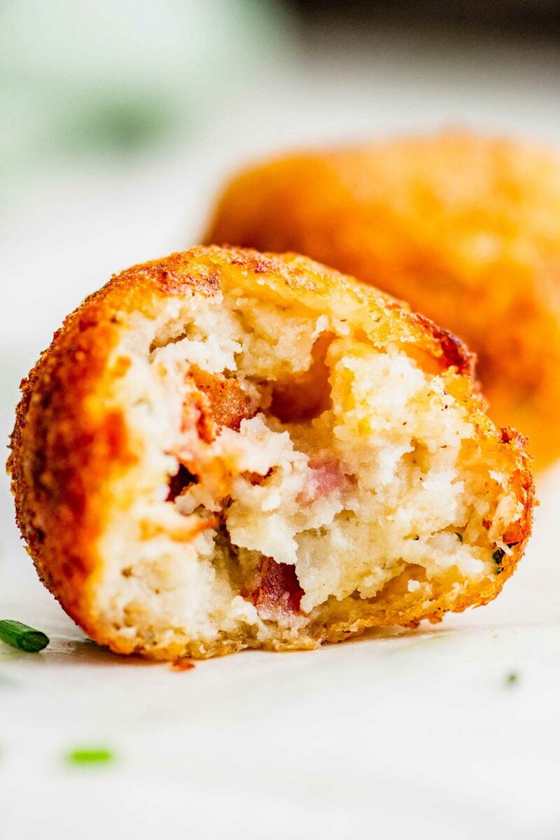 A bite has been taken out of a fried mashed potato ball.