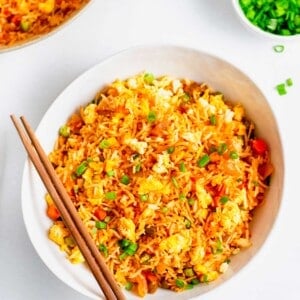 Overhead view of kimchi fried rice in white bowl with wooden chopsticks