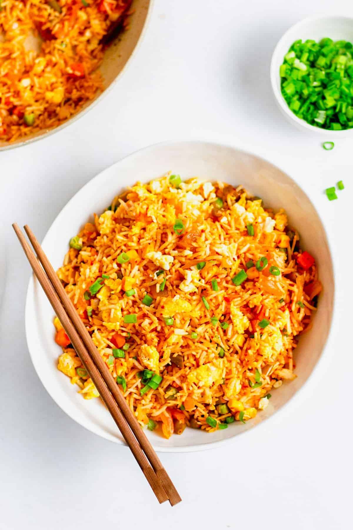 Overhead view of kimchi fried rice in white bowl with wooden chopsticks