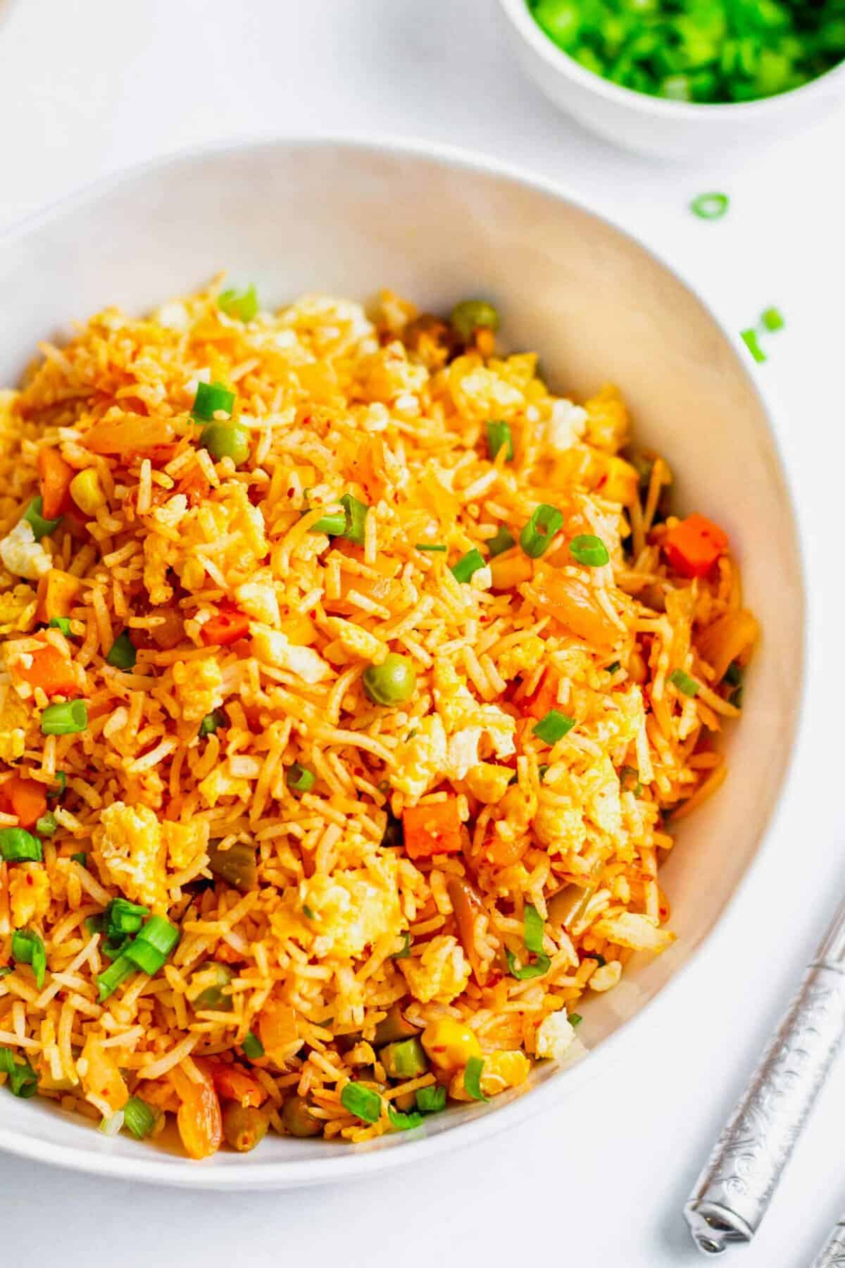 Kimchi fried rice in white bowl, garnished with green onions