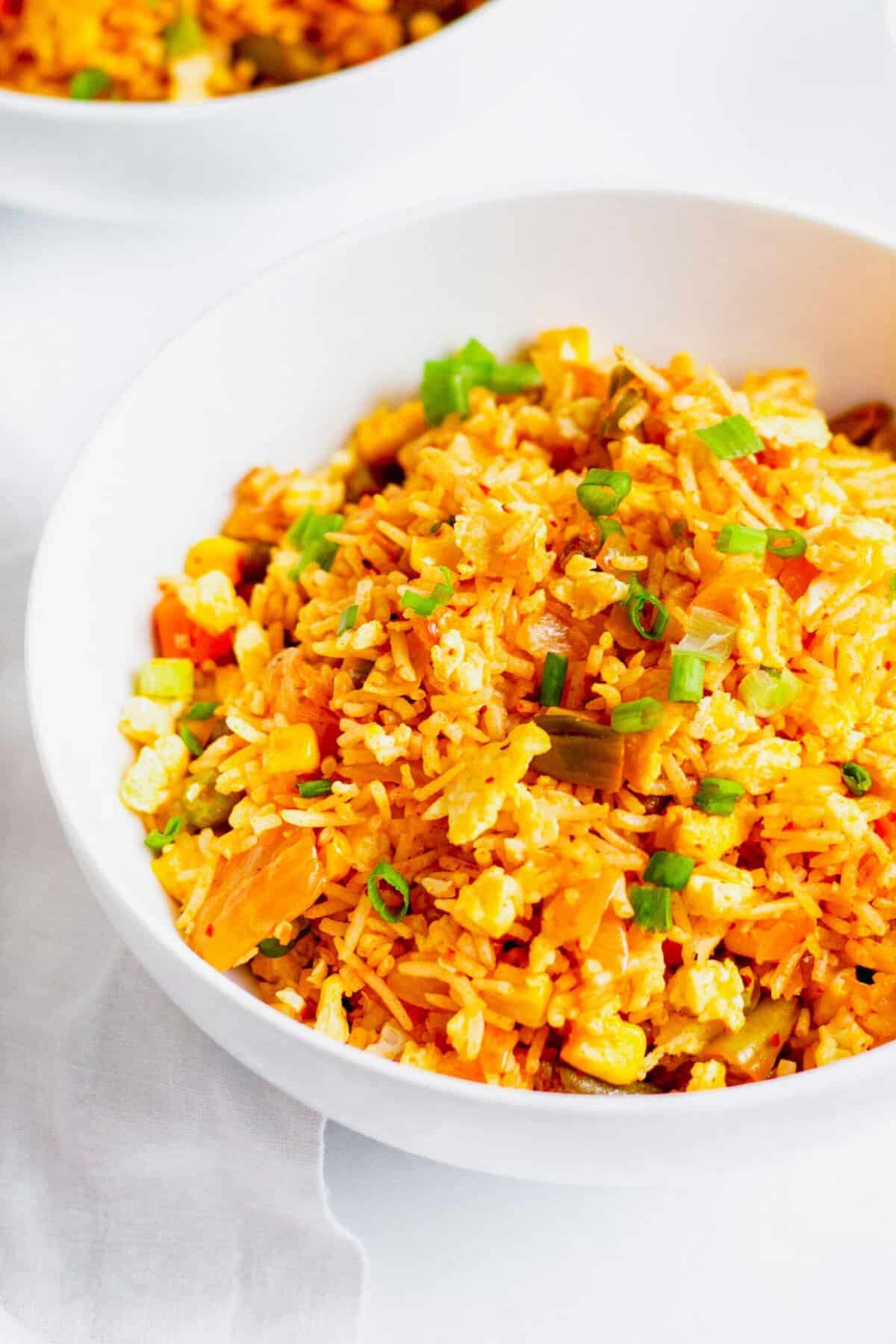 Kimchi fried rice in white bowl, garnished with green onions
