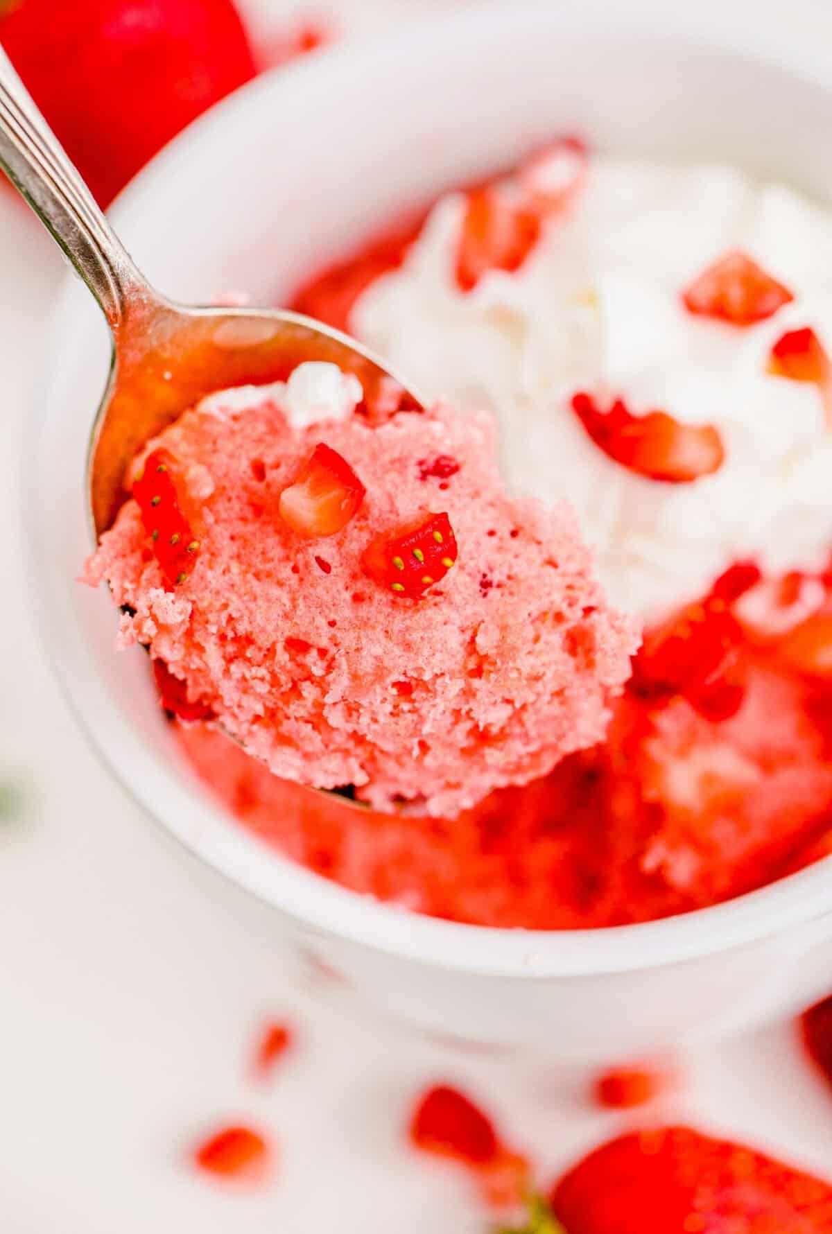 Spoonful of strawberry mug cake with diced strawberries