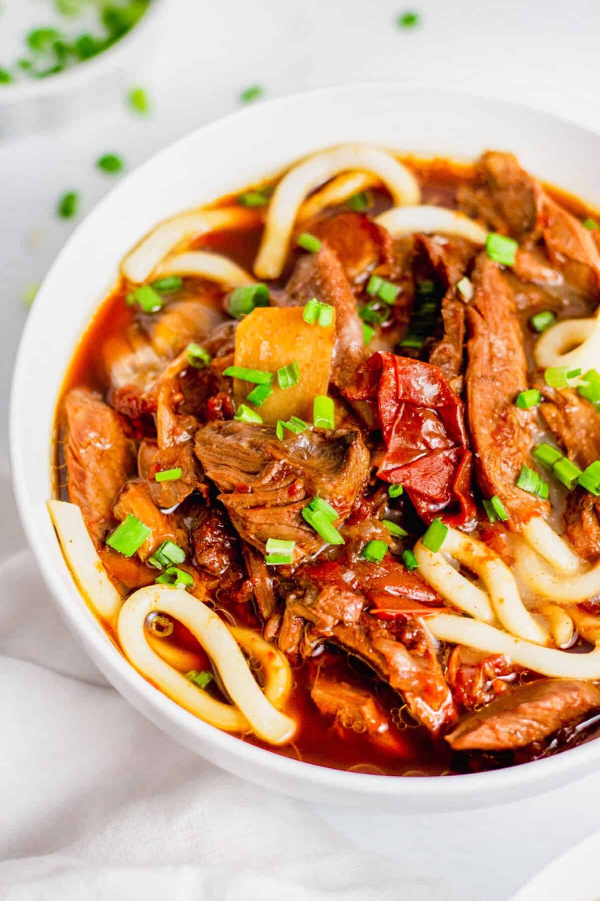 Bowl of Taiwanese beef noodle soup topped with minced green onions