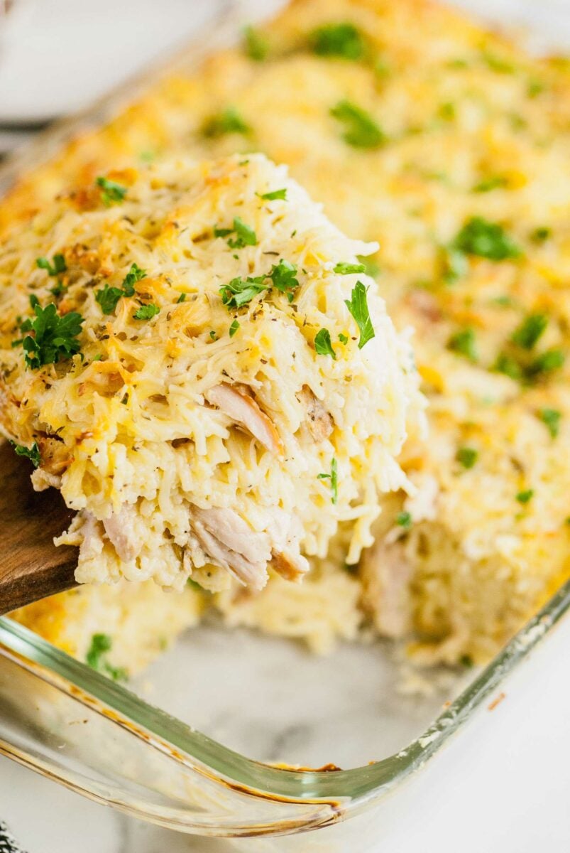 A serving of tetrazzini is being lifted from a serving dish. 