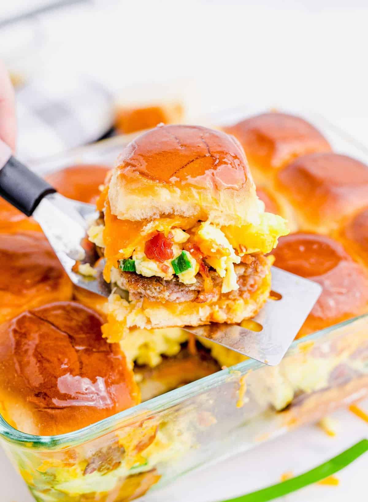 One breakfast slider being removed from baking dish