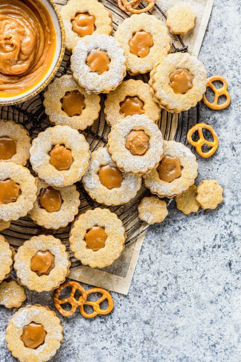 Cookies, pretzels, and extra caramel sauce are presented on a wire cooling rack.