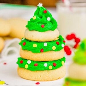 Three sugar cookies are stacked with green icing and sprinkles to resemble a Christmas tree.