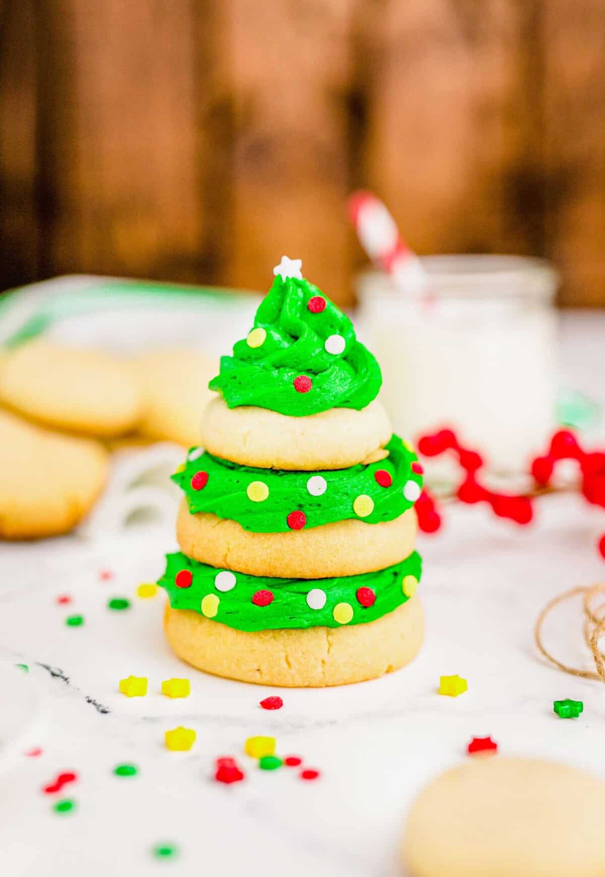 A large sugar cookie sits on the bottom of the tree, a medium sized cookie is in the middle, and a small cookie is on top, all sandwiched with green icing.