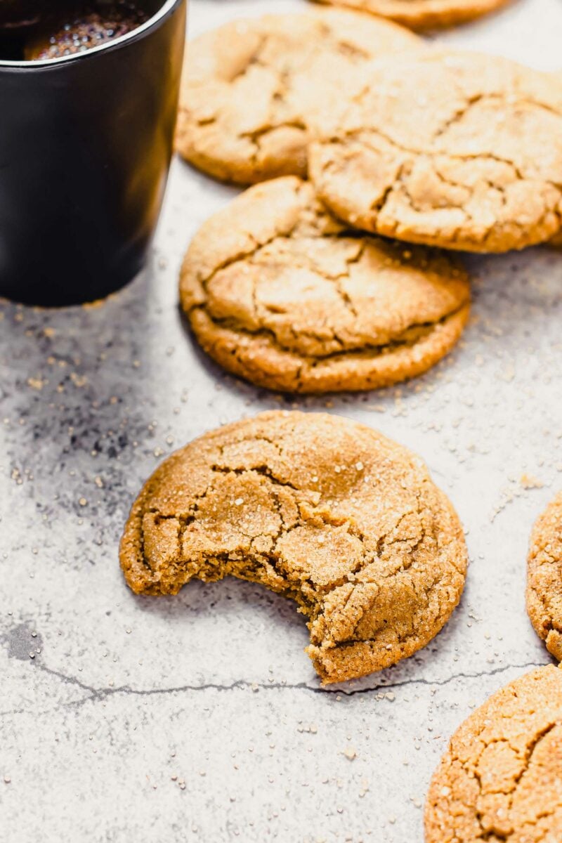 Several cookies are placed next to a mug filled with black coffee.