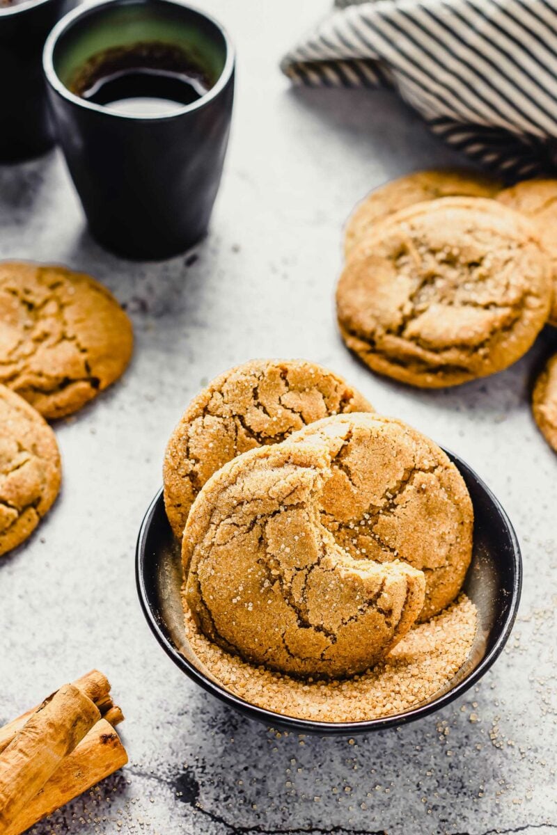 A few cookies are placed in a small black bowl with turbinado sugar. 