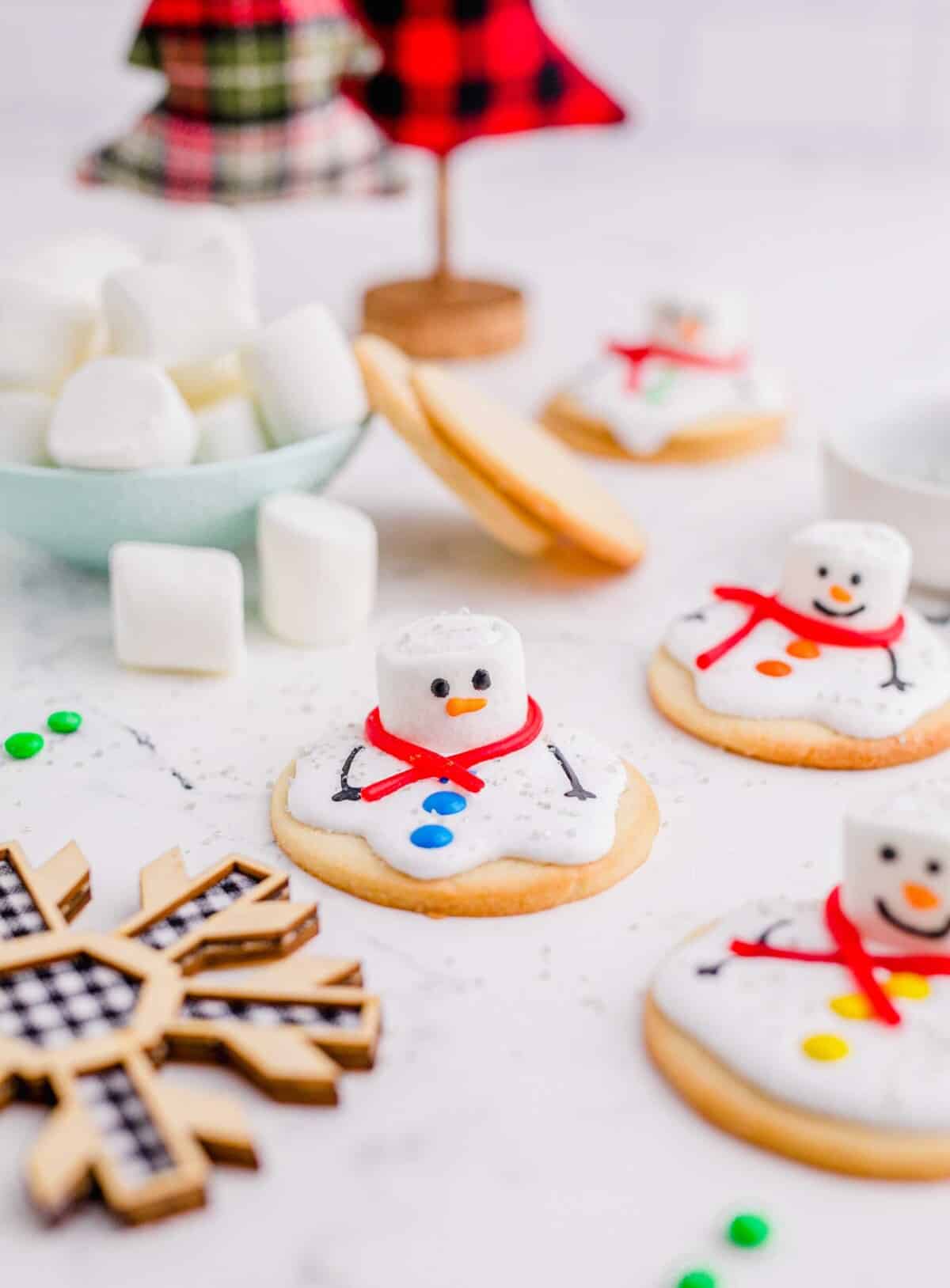 Several melted snowmen cookies are spread out on a white countertop.