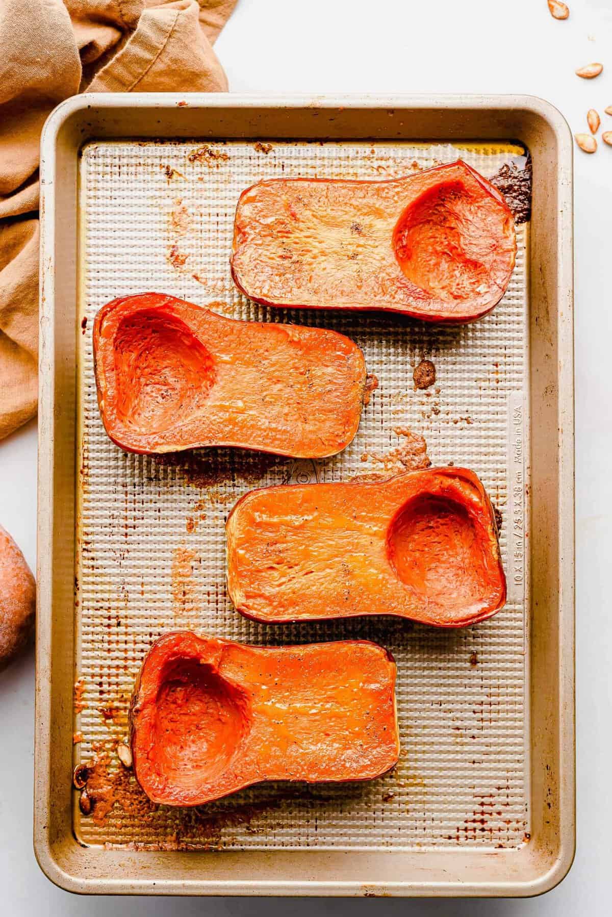 Overhead view of honeynut squash halves on baking sheet