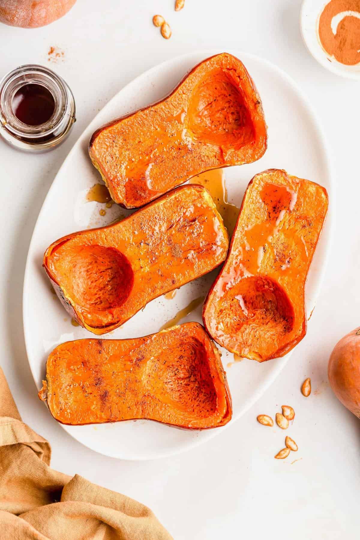 Roasted honeynut squash halves on white serving platter