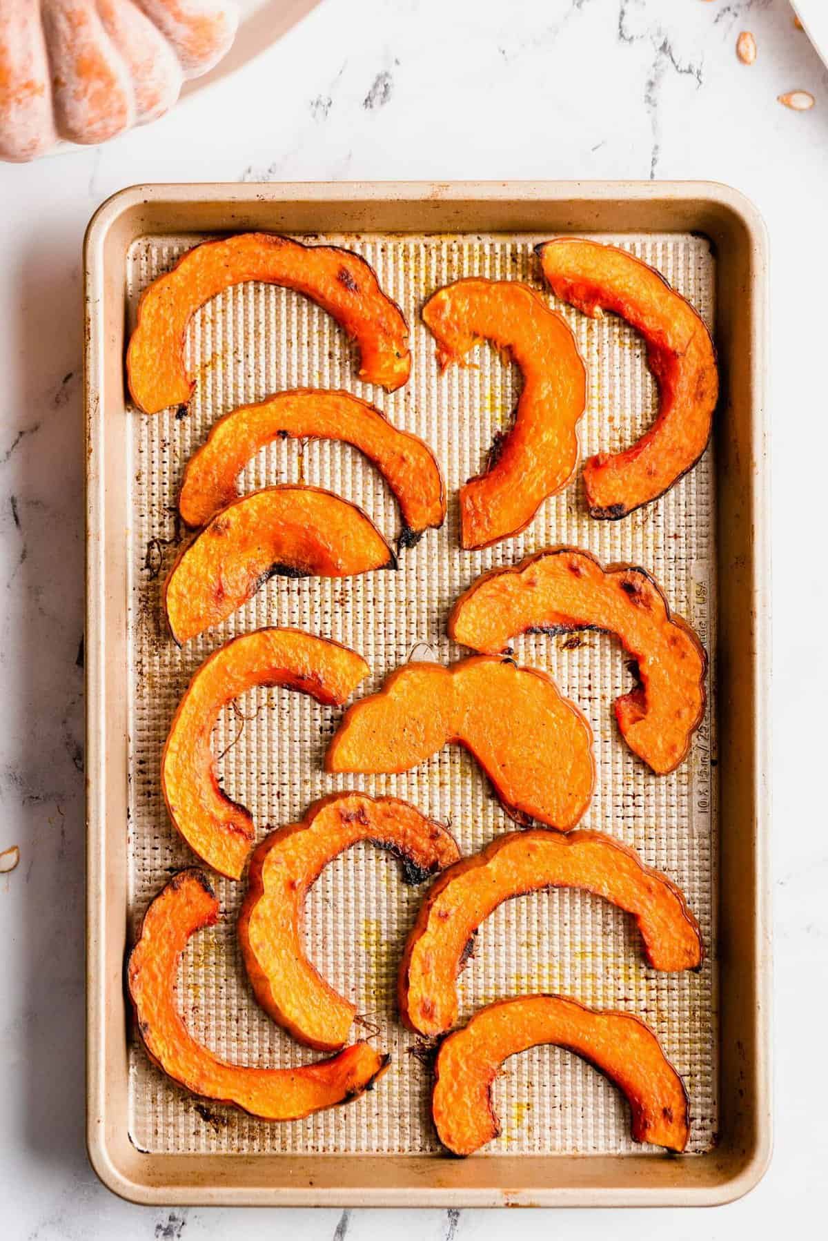 Overhead view of koginut squash slices on baking sheet after roasting