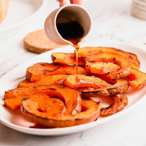 Pouring maple syrup over roasted koginut squash slices