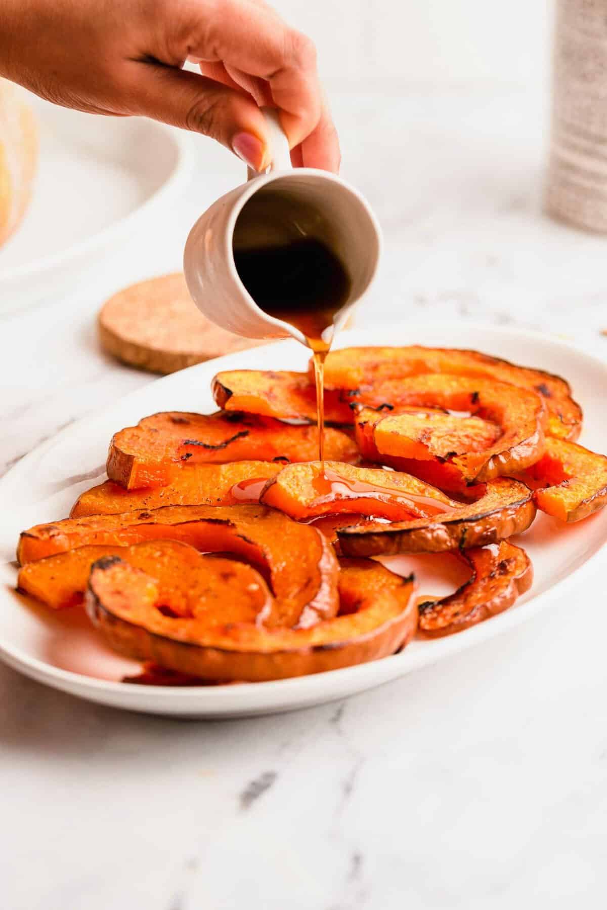 Pouring maple syrup over roasted koginut squash slices