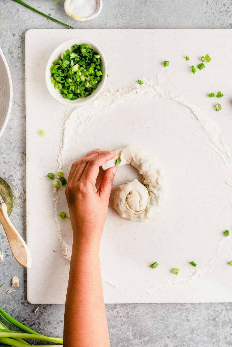 Overhead view demonstrating scallion pancake dough being twisted into spiral