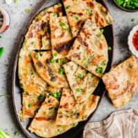 Overhead view of scallion pancakes on platter with scallions scattered over the top