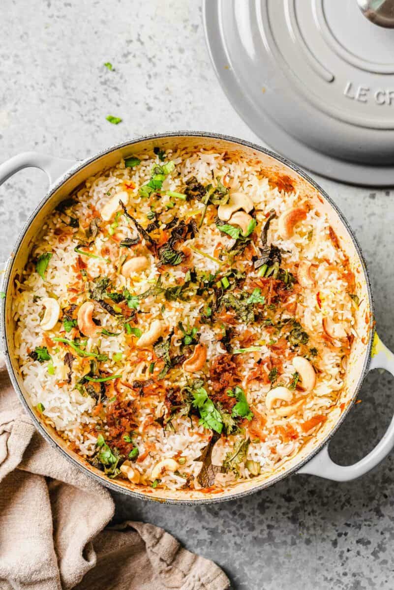 A dutch oven is filled with cooked vegetable biryani. 
