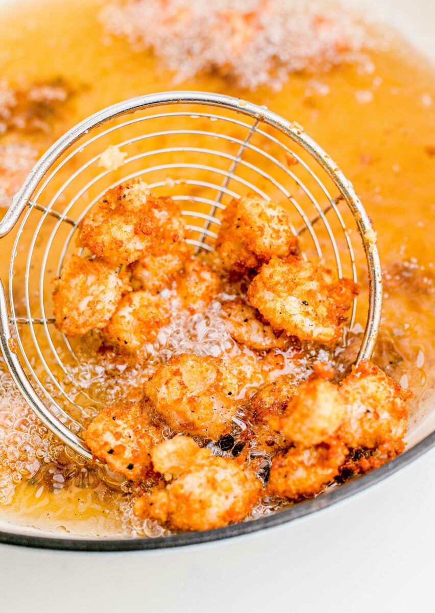 A batch of shrimp are being deep fried in oil. 
