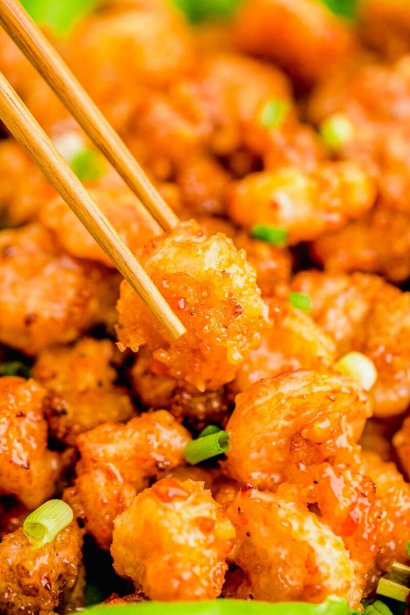 A bang bang shrimp is being lifted from the batch with chopsticks. 