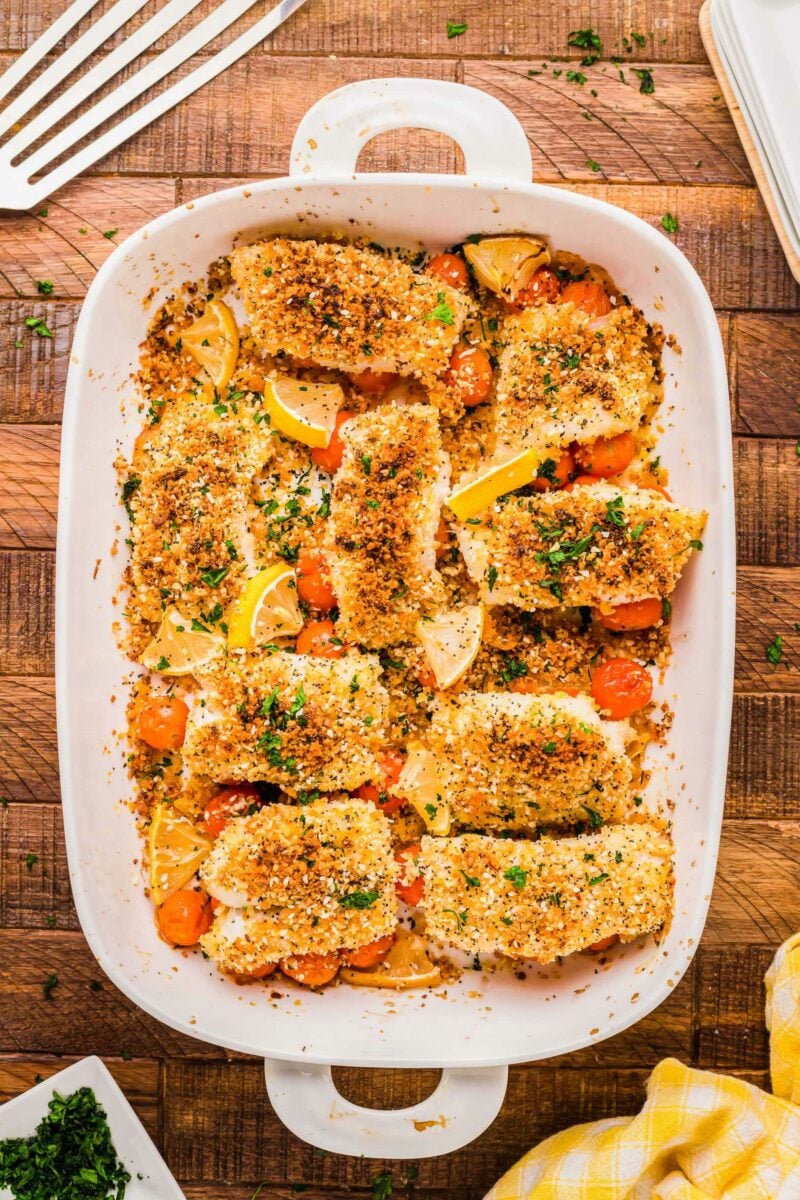 A batch of baked cod filets is presented in a white baking dish.