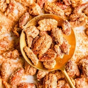 Round gold spoon resting on sheet pan, filled with spiced nuts