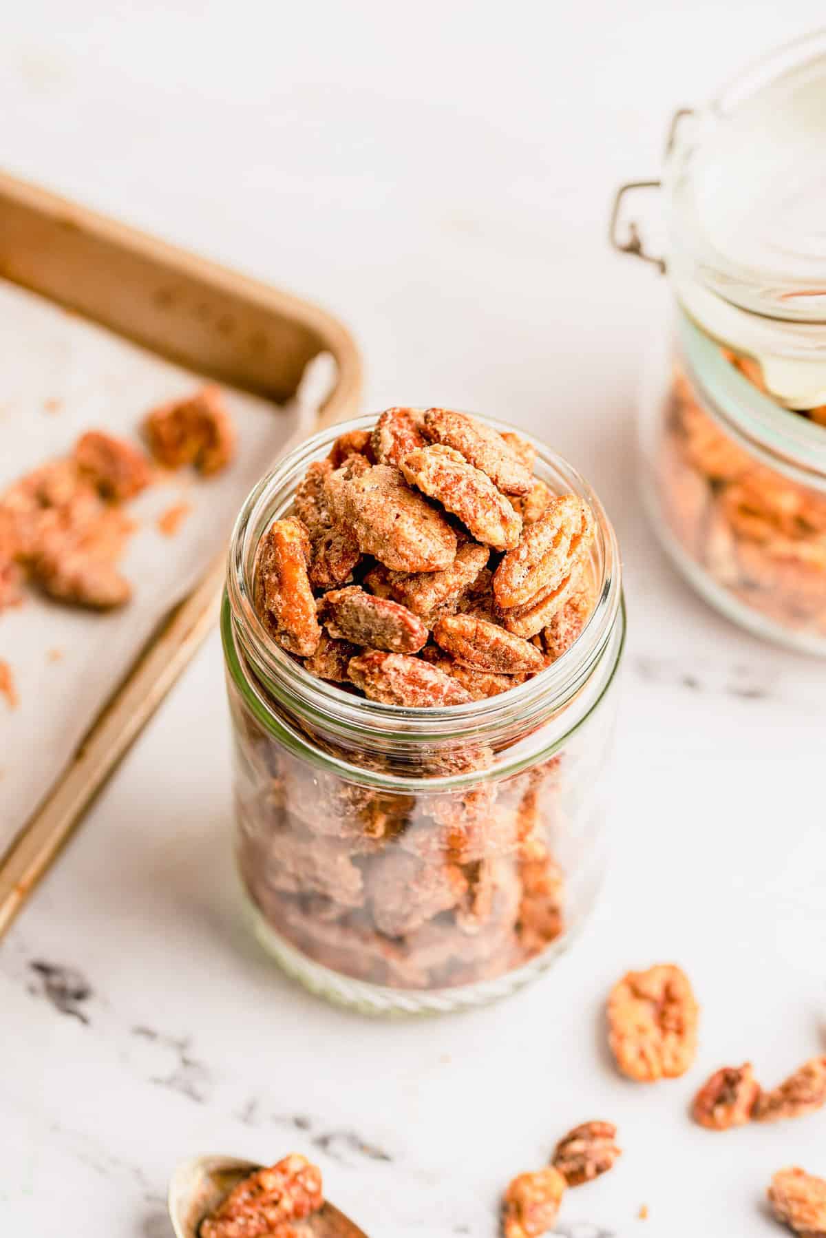 Spiced nuts in glass jar with nuts scattered in foreground
