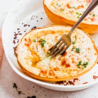 Fork digging into cheesy pesto spaghetti squash boat