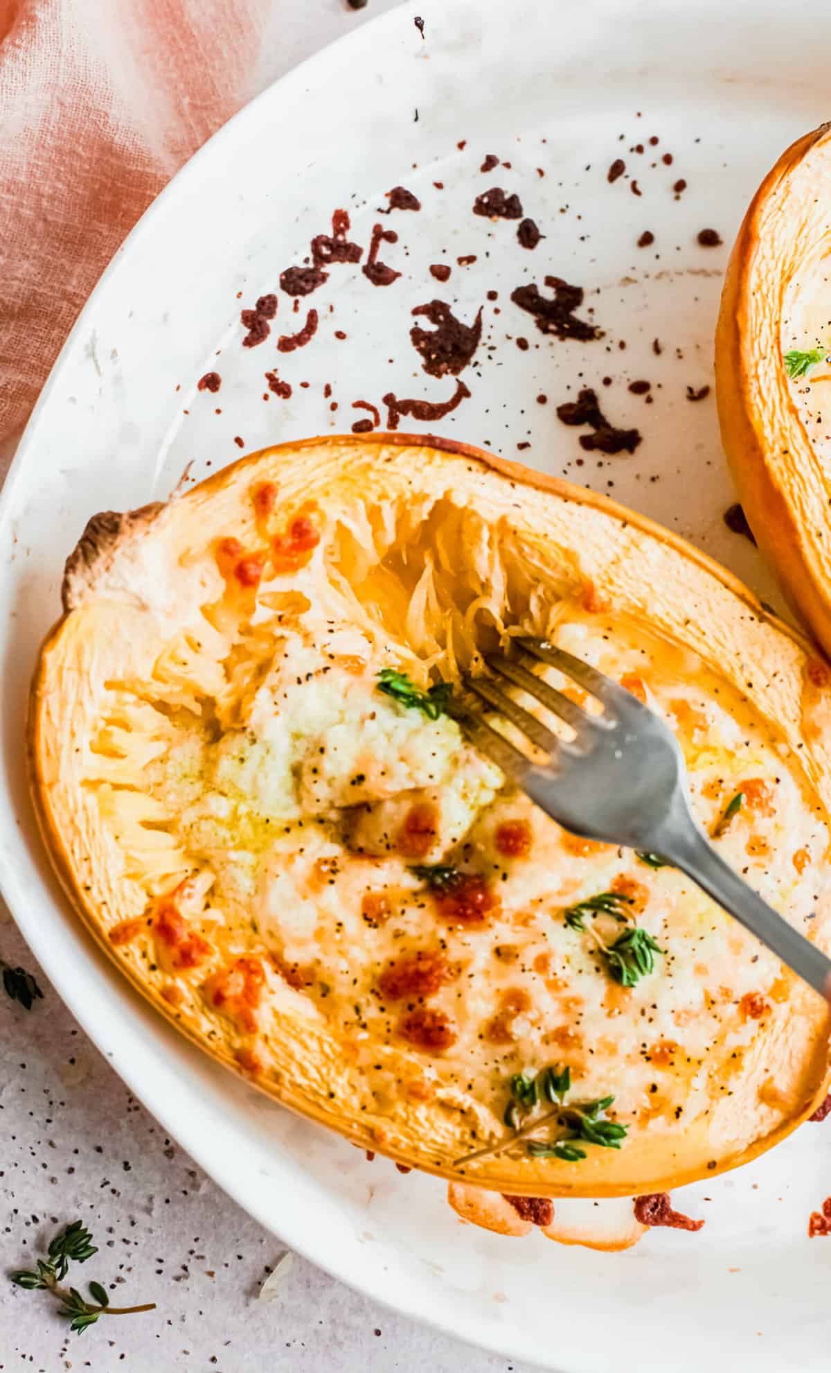 Overhead view of fork shredding baked cheesy spaghetti squash