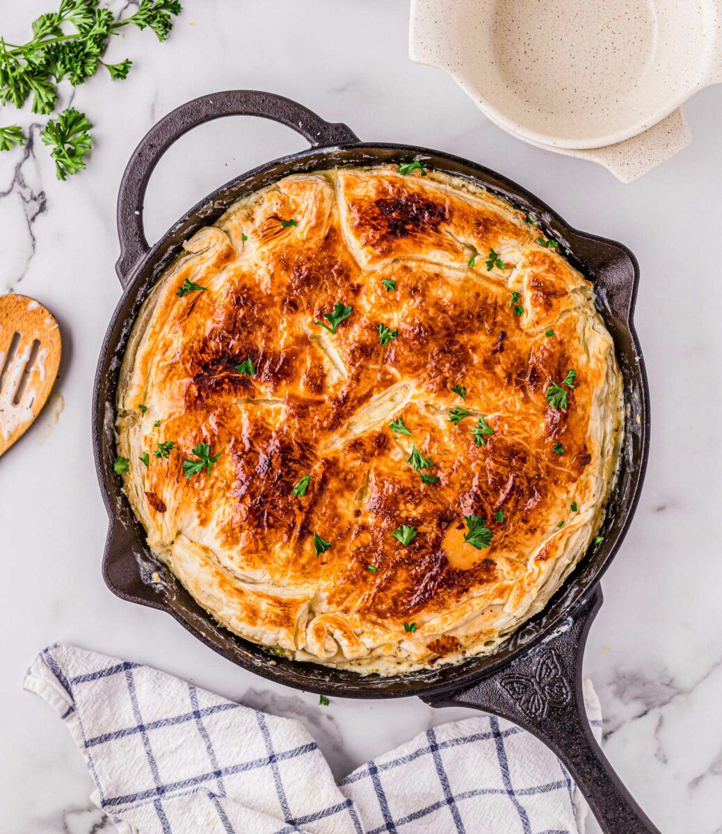 A black cast iron skillet is filled with cooked pot pie.