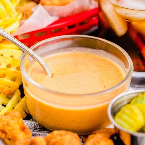 Glass bowl of Chick-Fil-A sauce, surrounded by nuggets and fries