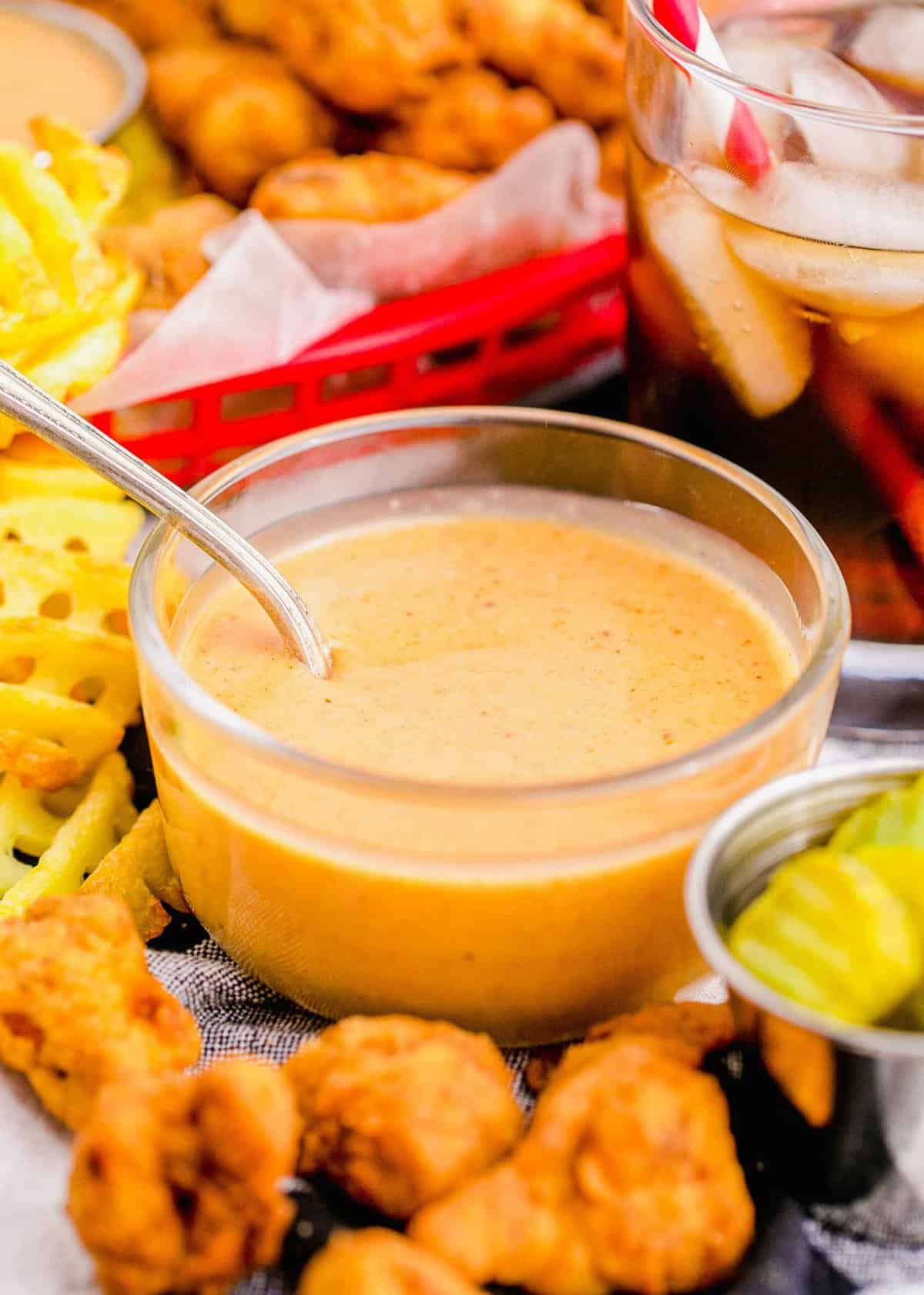 Glass bowl of Chick-Fil-A sauce, surrounded by nuggets and fries