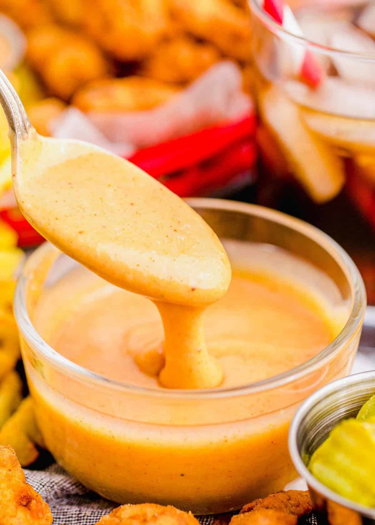 Spoonful of Chick-Fil-A sauce dripping into small glass bowl of sauce