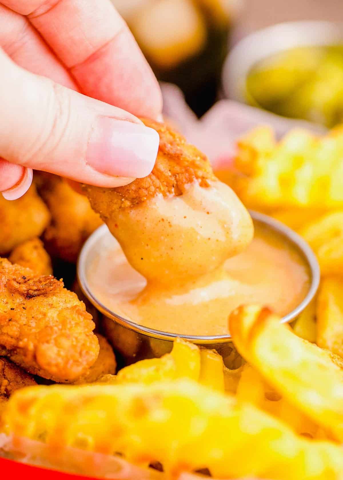 Hand dipping nugget into Chick-Fil-A sauce