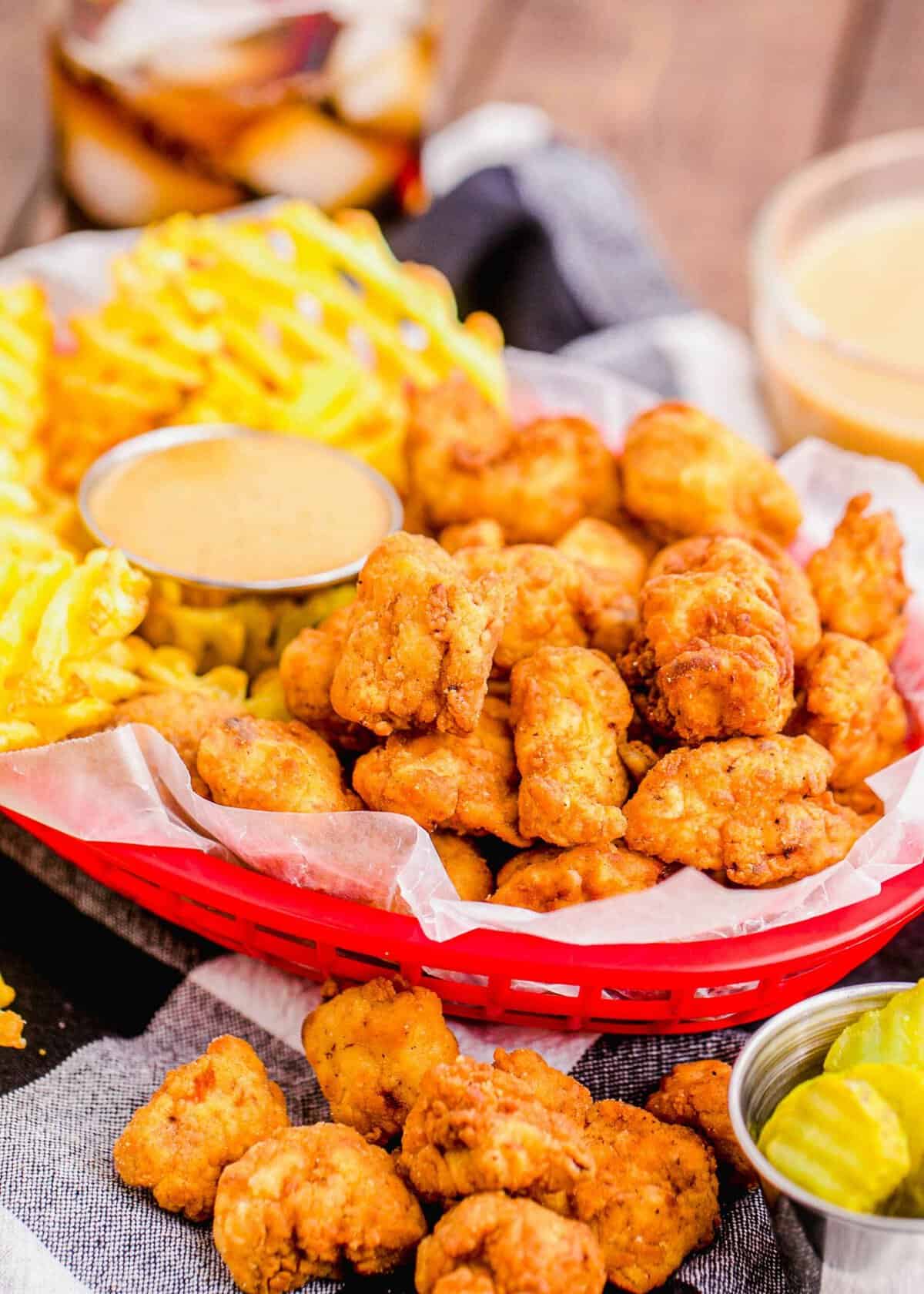 Chicken nuggets in basket with dipping sauce and waffle fries