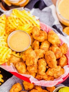 Overhead view of chicken nuggets in basket with waffle fries and dipping sauce
