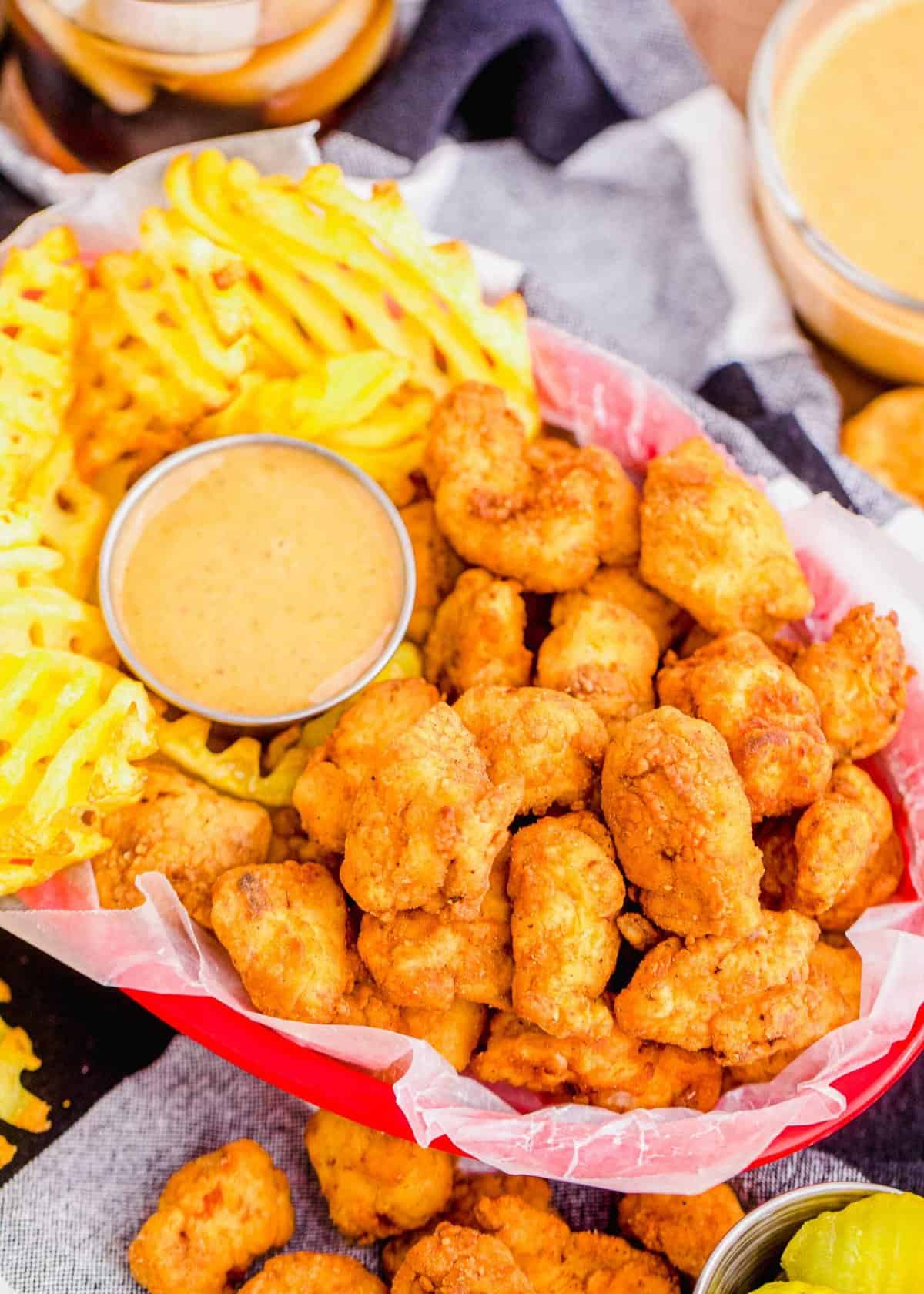 Overhead view of chicken nuggets in basket with waffle fries and dipping sauce