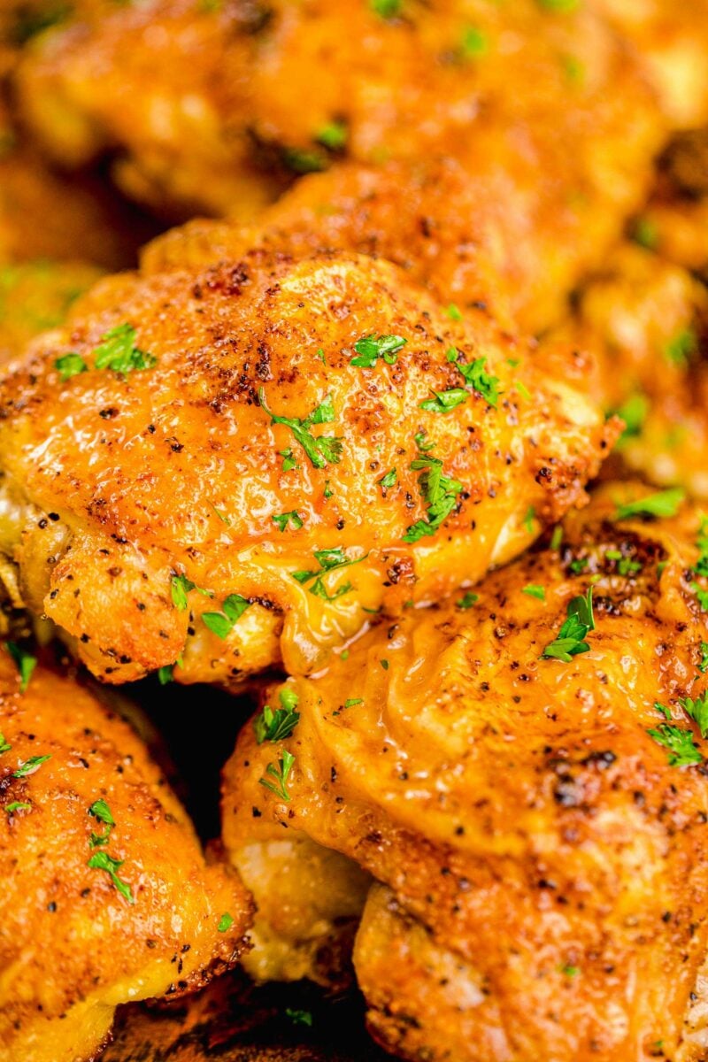 Fresh parsley is garnishing a serving of crispy baked chicken thighs. 