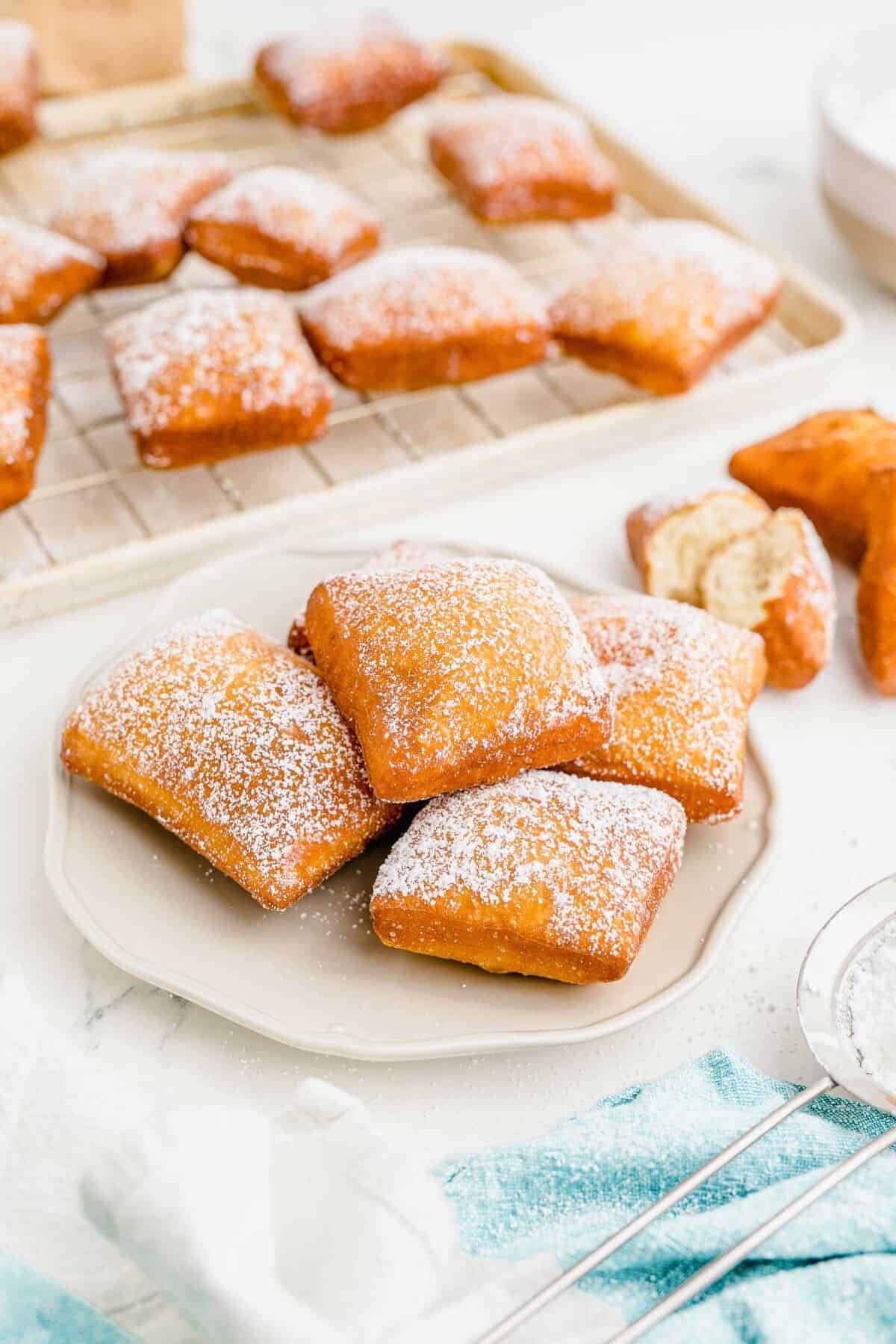 A white plate is topped with five ready to eat beignets.