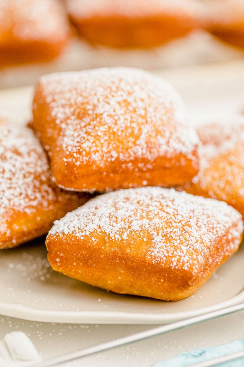 A plate of beignets has been dusted with white powdered sugar. 