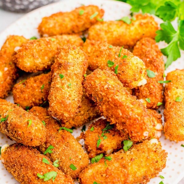 mozzarella sticks on a white plate next to fresh parsley