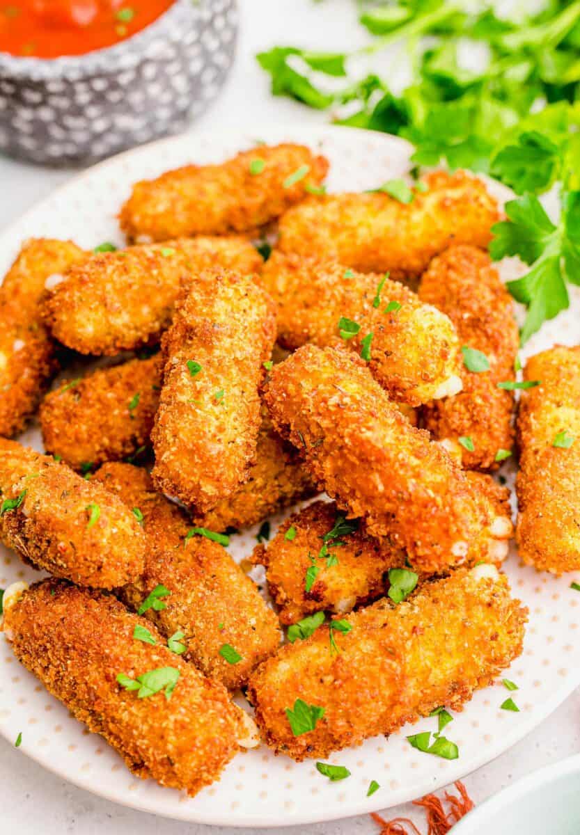 A stack of mozzarella sticks is sprinkled with fresh parsley.