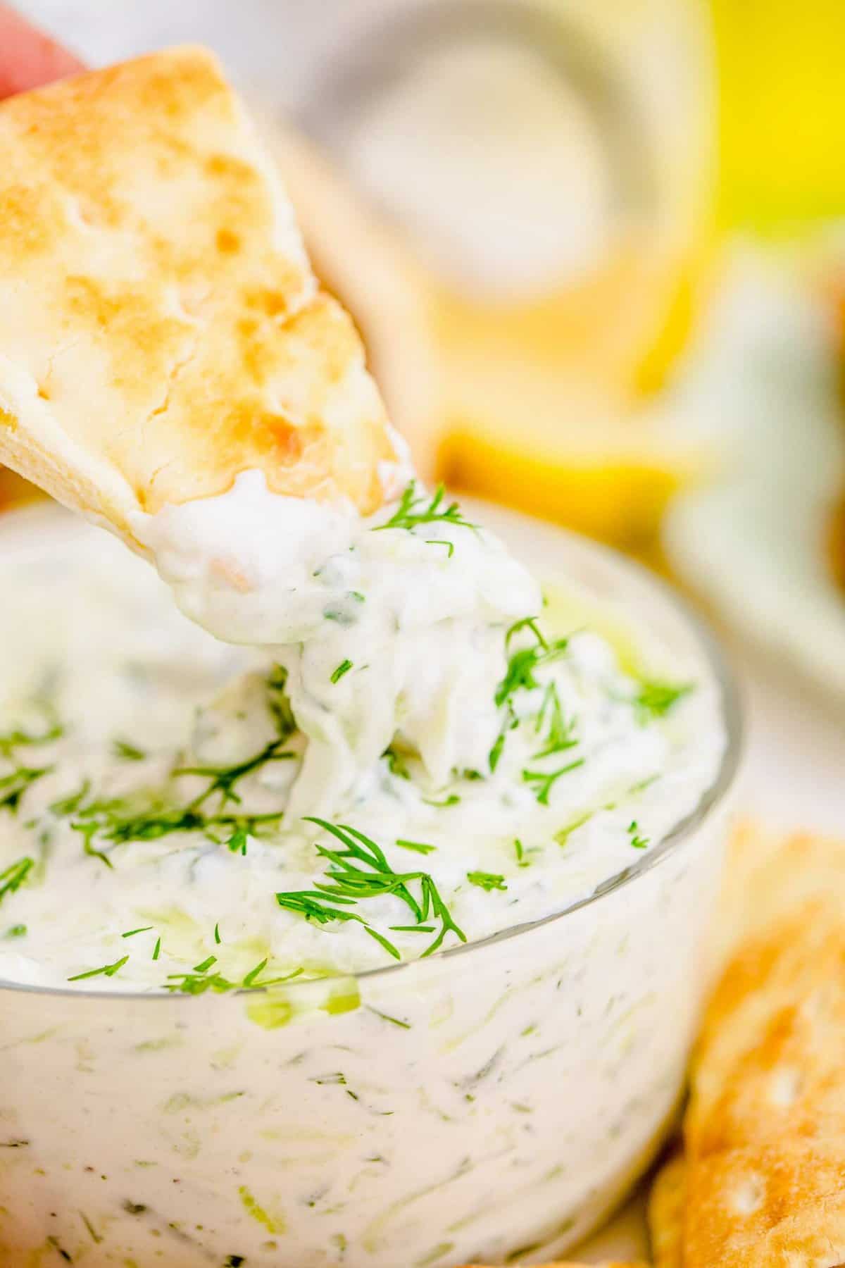 Pita chip being dipped into tzatziki