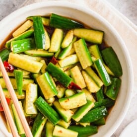 Overhead view of Chinese cucumber salad in white bowl with chopsticks