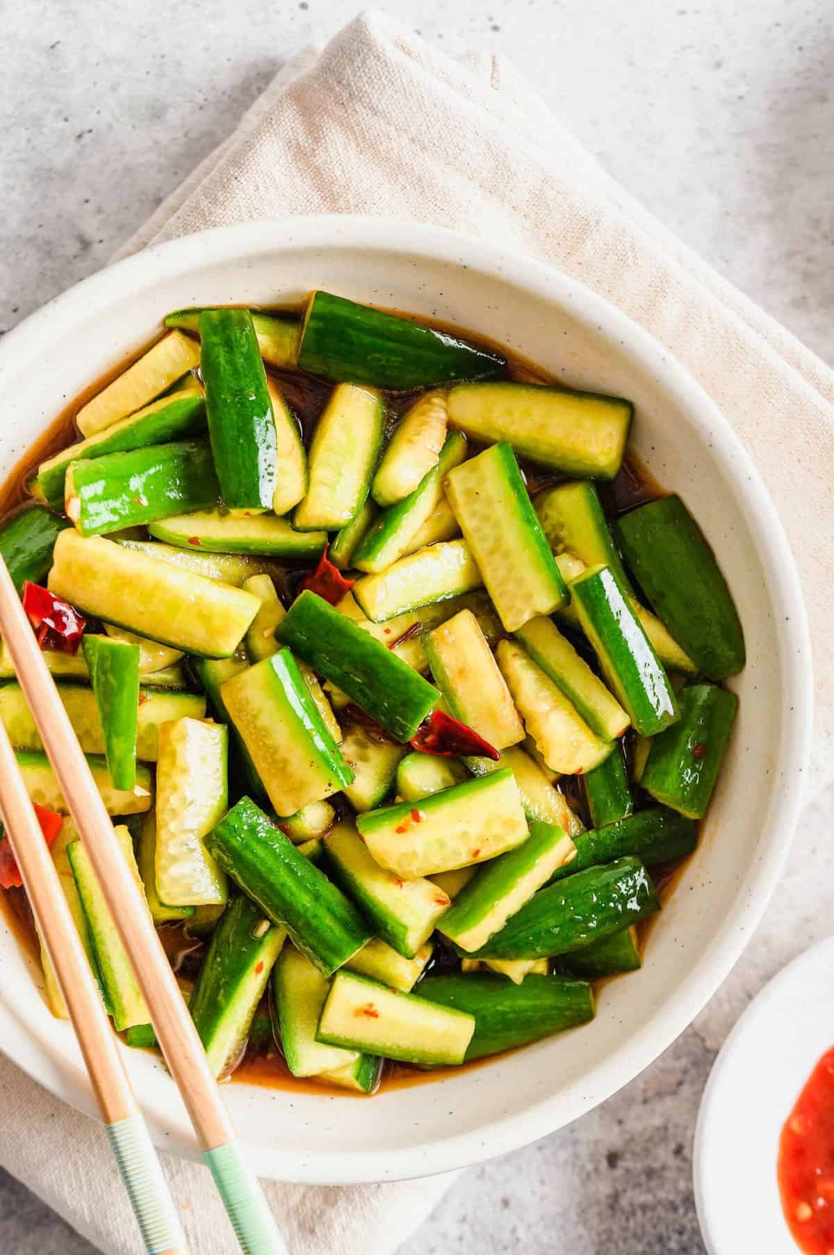 Overhead view of Chinese cucumber salad in white bowl with chopsticks