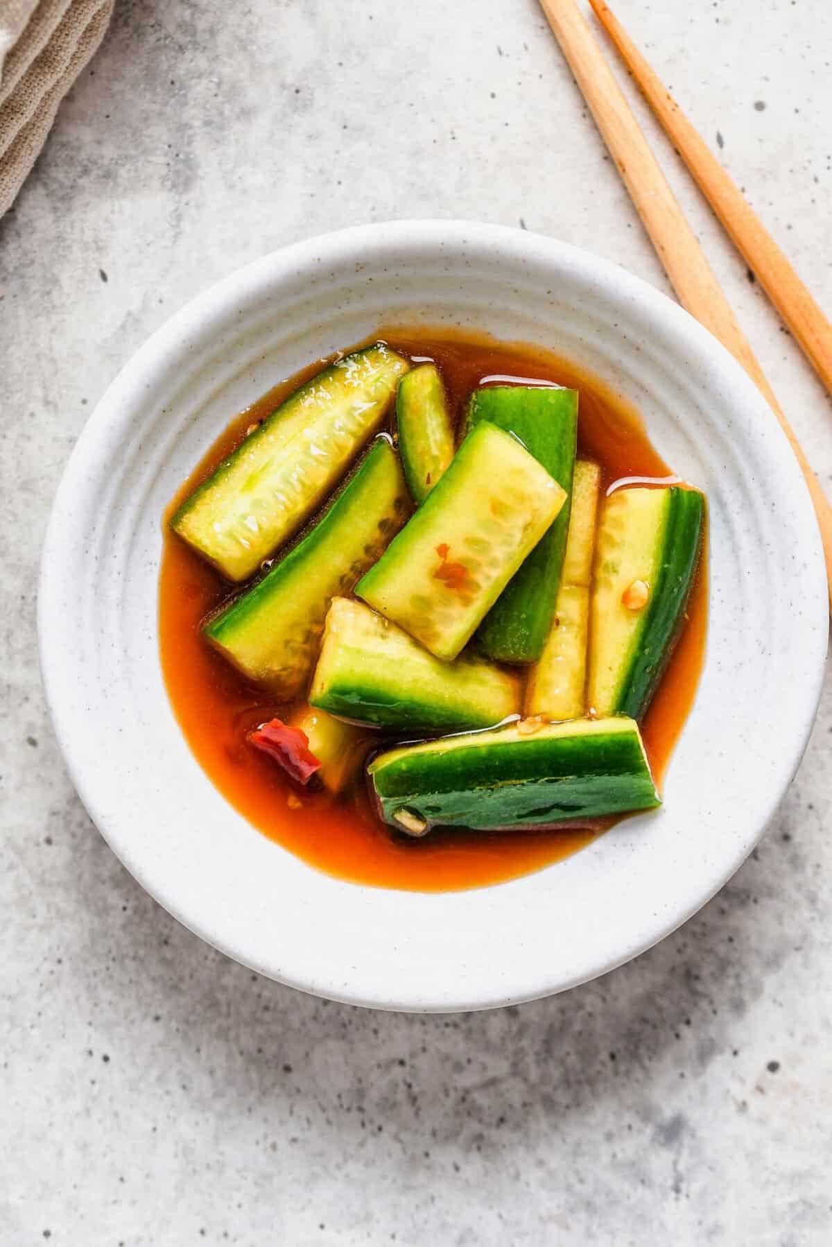 Overhead view of white bowl with Chinese cucumber salad and chopsticks