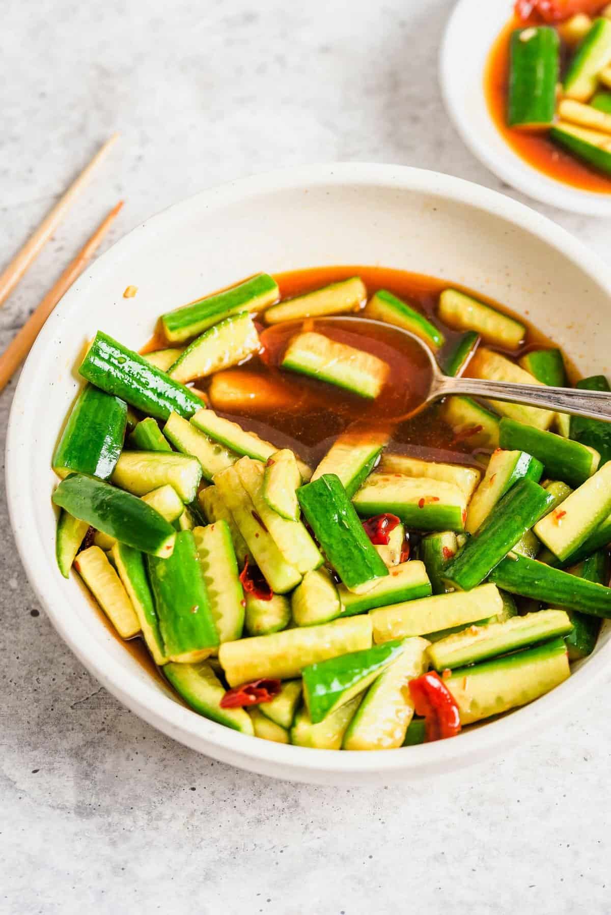 Chinese cucumber salad in white bowl with spoon