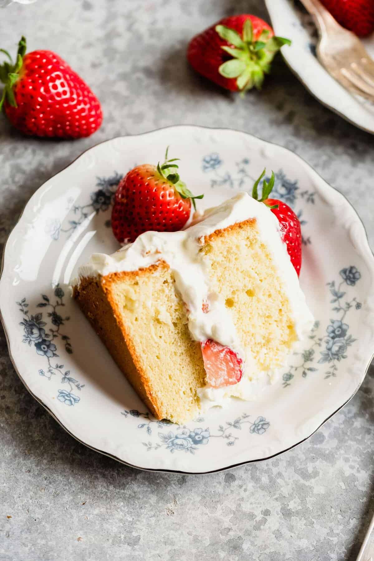 Slice of strawberry sponge cake on plate, garnished with fresh strawberries