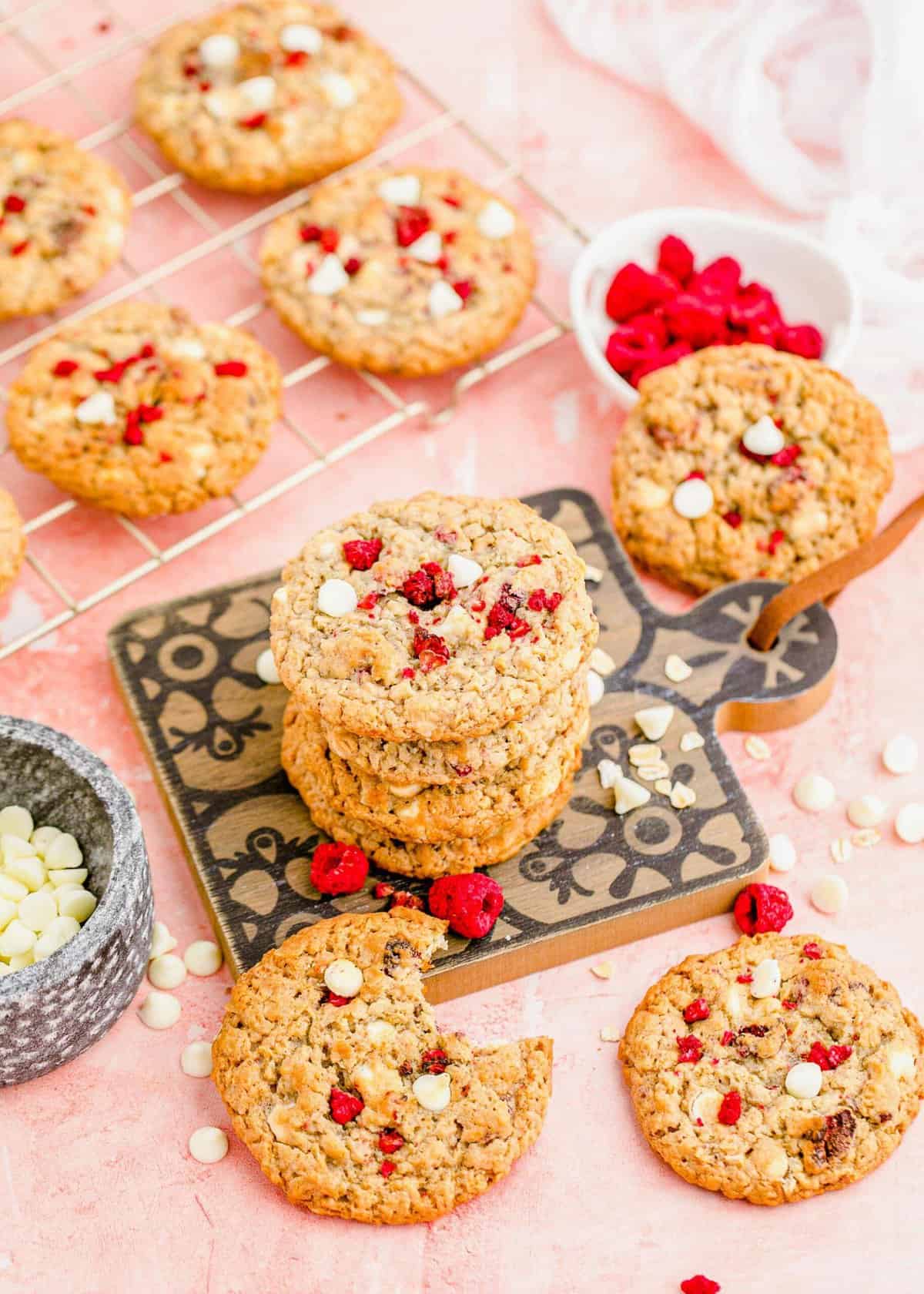 White chocolate raspberry cookies stacked on decorative wooden board